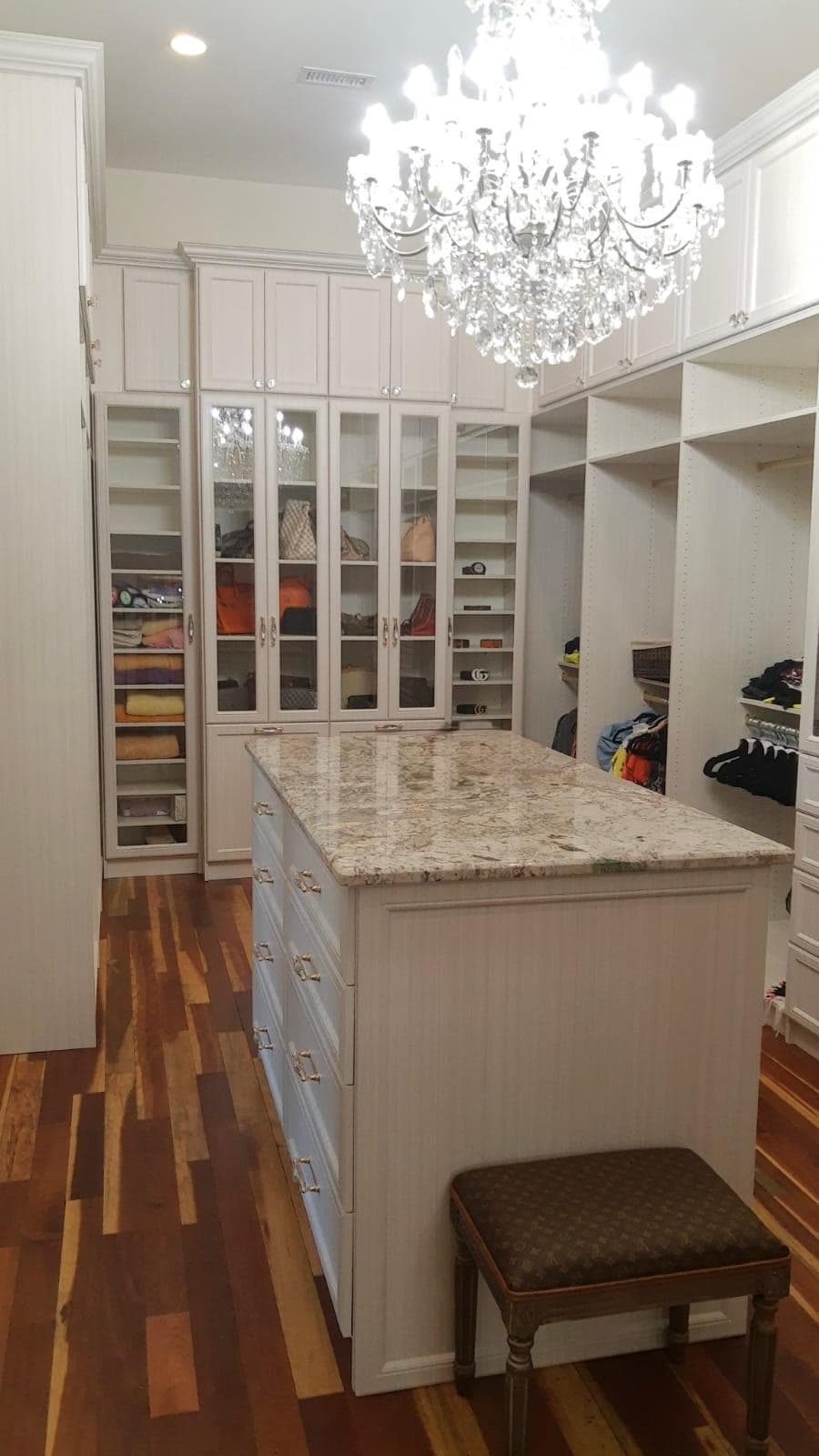 Luxury custom walk-in closet with granite-top island and crystal chandelier