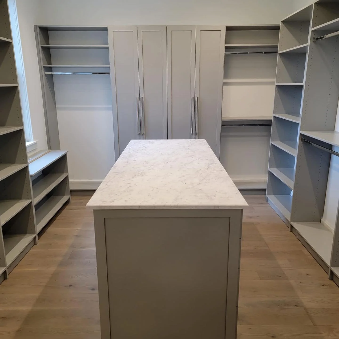 Custom walk-in closet with grey shaker doors and marble-top island