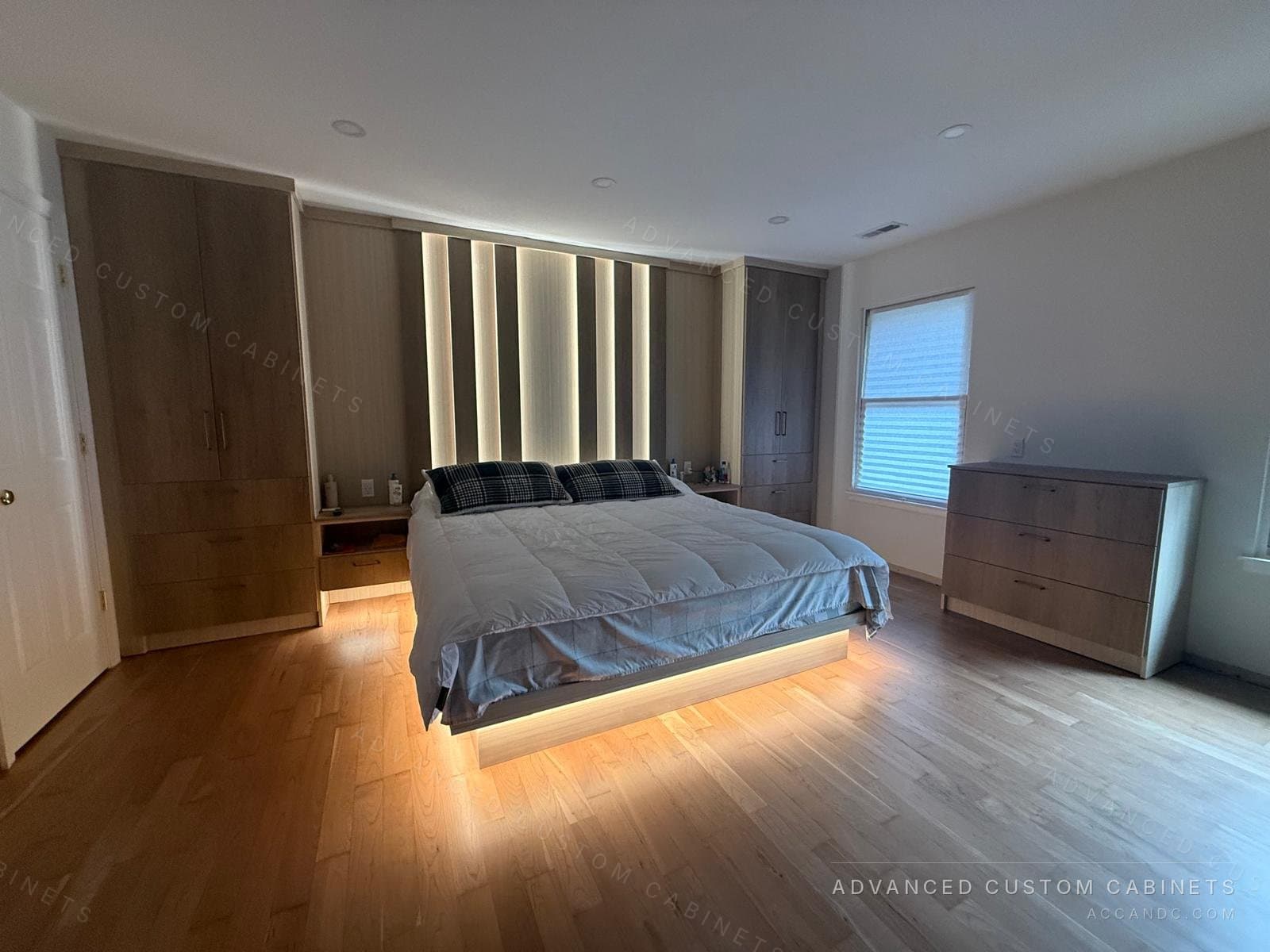 The same custom bedroom with the slatted headboard panel and the platform bed lit by built-in LED strips