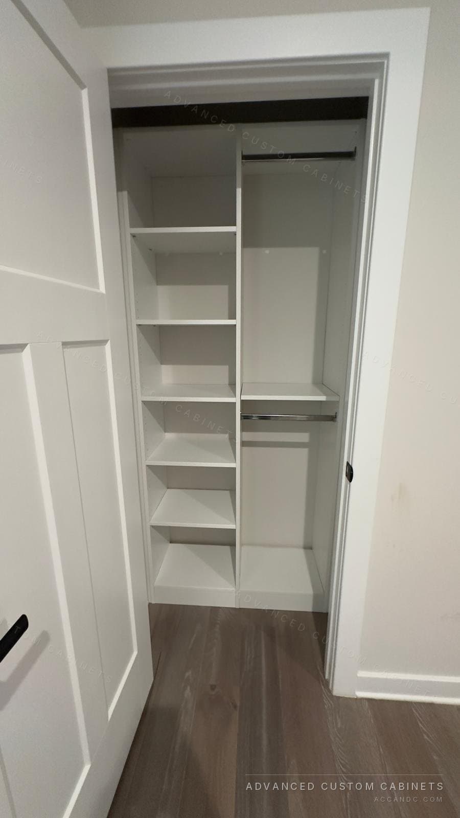 White reach-in closet behind a shaker door with a narrow tower of open shelves beside double hanging rods