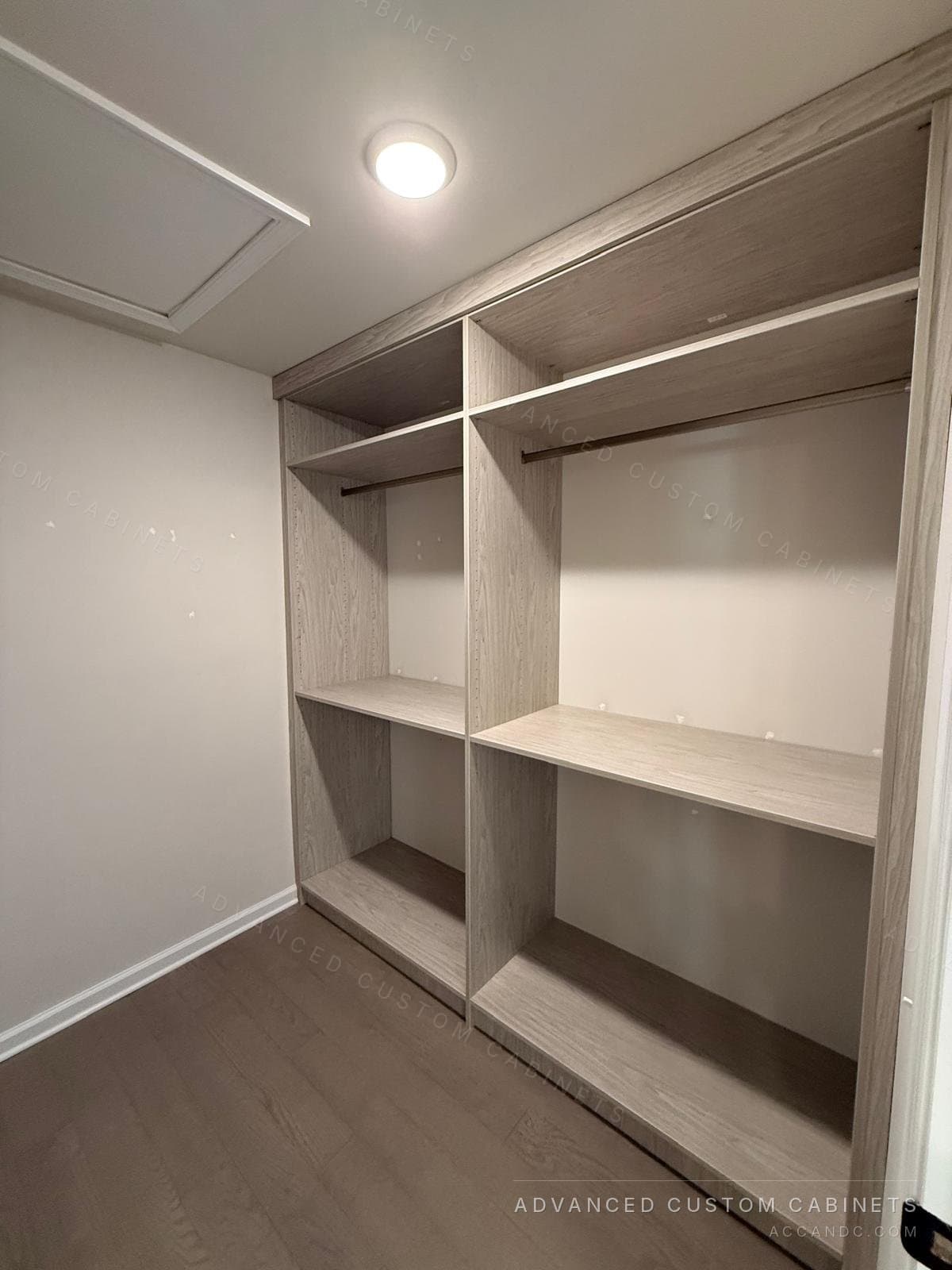 Grey-oak walk-in closet wall with upper shelving, double hanging rods and a shoe shelf