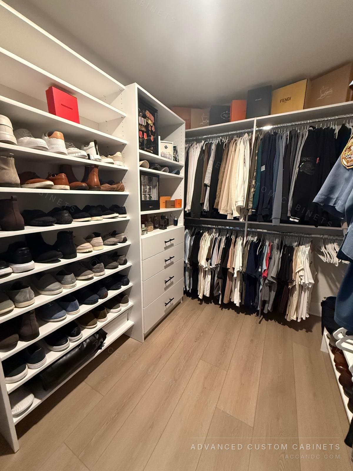 White walk-in closet with a full wall of open shoe shelves, a tower of open shelves over four drawers with black bar pulls and double hanging along the back wall