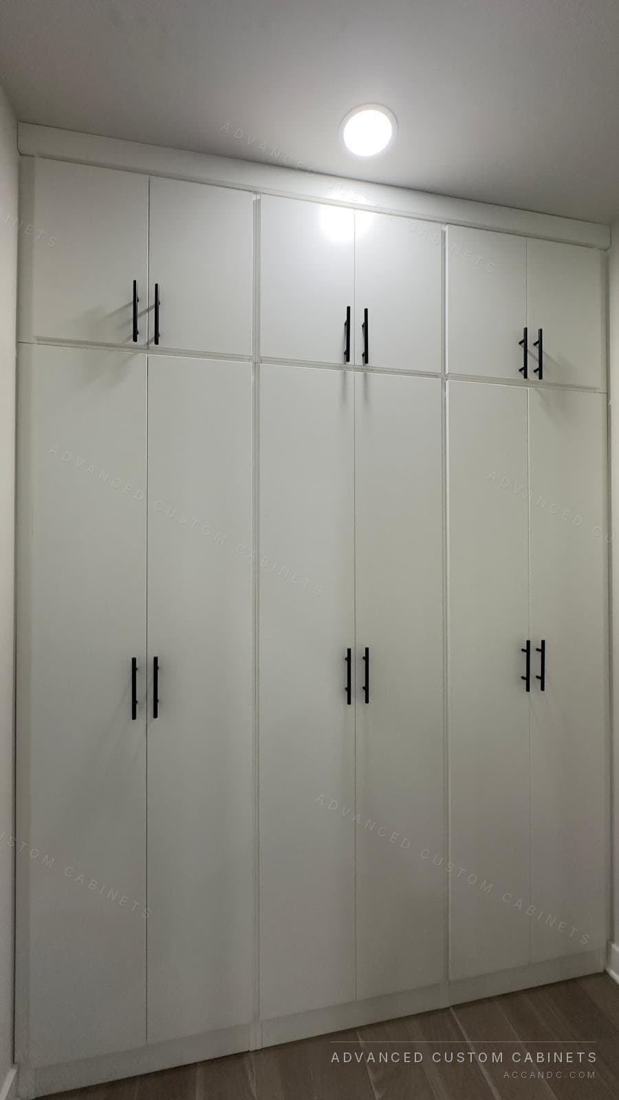 White wardrobe wall with four full-height doors and black bar pulls, fitted wall to wall