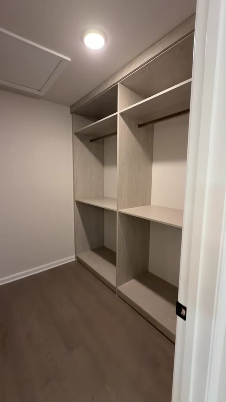 Grey-oak walk-in closet with double hanging and shelf towers under a recessed light, video walkthrough